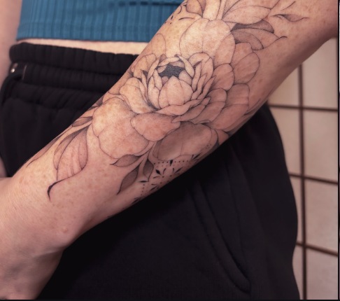 Fine-line botanical forearm tattoo with roses and foliage