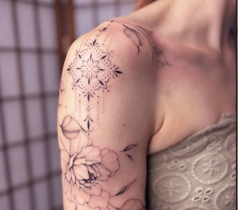 Floral spray fine-line tattoo across the shoulder